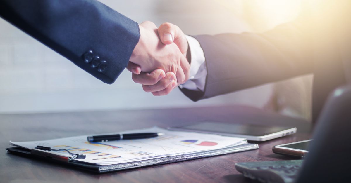 Professional handshake agreement over business charts in an office setting.
